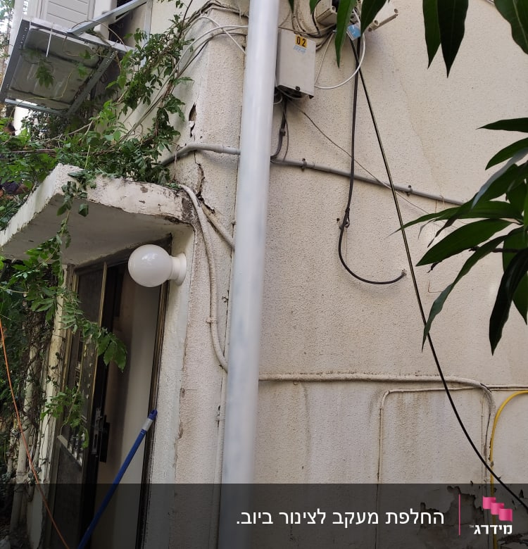 צינור פלסטיק לבן מחובר לקיר חיצוני של בניין